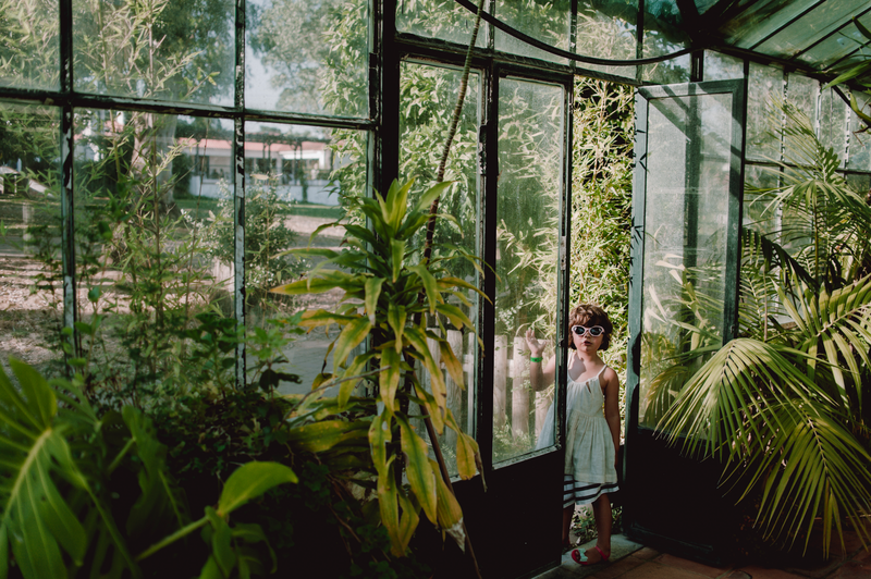 Girl wearing sunglasses standing near a greenhouse door